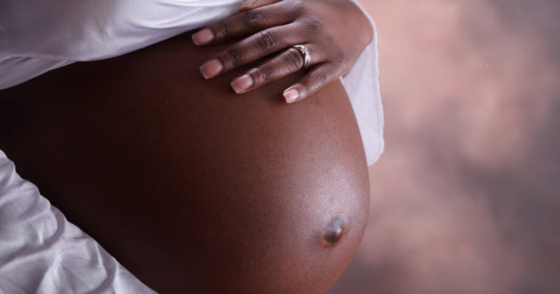 Close-up of the exposed belly and hand of a pregnant woman