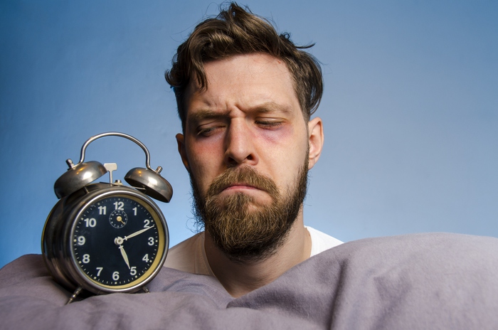 Closeup, man looking angry at the alarm clock , insomnia concept